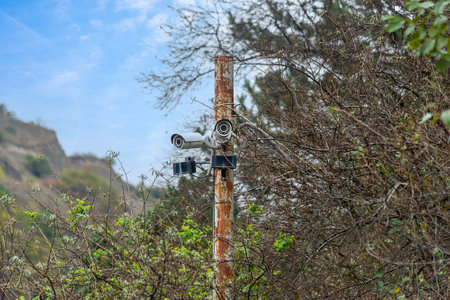 video surveillance cameras on a pole in the bush against a backdrop of mountains and blue sky, guarding private property and nature reservesの写真素材
