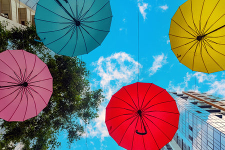 View from below of multicolored umbrellas suspended against a blue sky with clouds. Bright and positive picture.の写真素材
