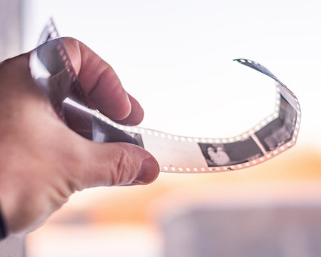 Film photography, hand developing film, analog photography. Examining film, hand holding a developed strip of film. Photographic materialsの写真素材