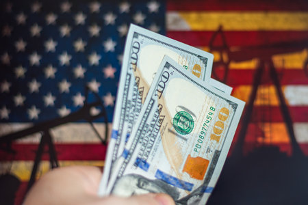 Hand holding money in front of American oil industryの写真素材