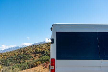 White travel van back of a white van in the mountains, under a blue sky with landscape backdrop parked in the nature.の写真素材