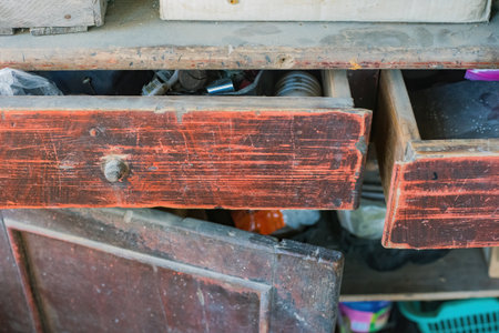 Distressed cabinet with red details, rustic wooden cabinet with open drawers, filled with odds and ends.の写真素材