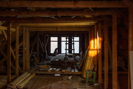 attic framework shows an interior filled with beams and tools, suggesting an ongoing renovation project in the space with the natural wood and light.の写真素材