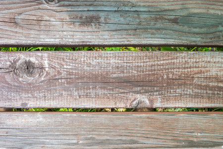 close-up view of weathered wooden planks with green grass in the backgroundの写真素材