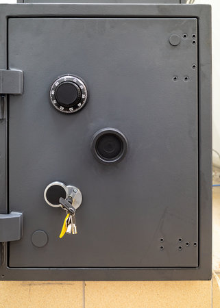 Gray safe with combination lock, keyhole, and keys hanging. Secure storage with a rugged, protective...