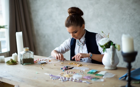 Girl made jewelry on wood table handmadeの写真素材