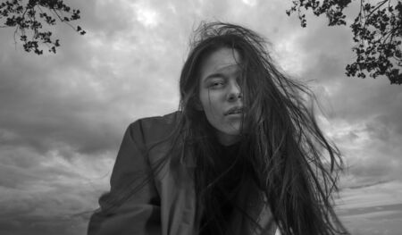 Portrait of beautiful brunette girl wearing raincoat on beach