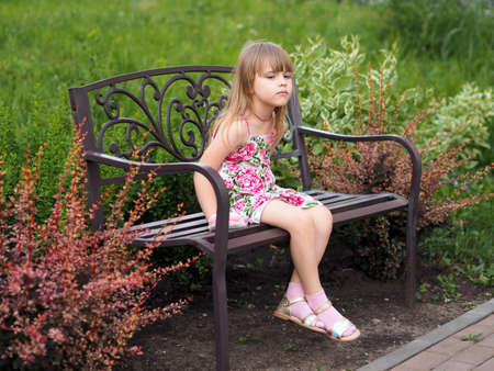 a young girl on a bench among beautiful green spaces summerの写真素材