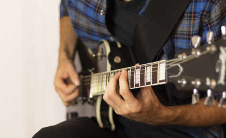 Musician playing guitar in sound recording studio. Rocker playing on electric guitar, closeup.の写真素材