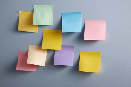 Colorful sticky notes arranged on a grey wall for remindersの素材