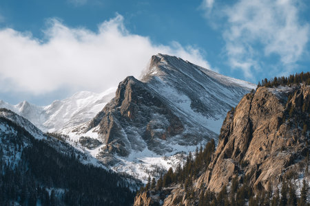 Snow-capped mountain peak rises under a clear blue skyの素材