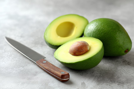 Freshly sliced avocados on a kitchen counter with knifeの素材