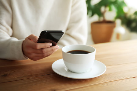 Enjoying coffee while checking messages on a smartphoneの素材