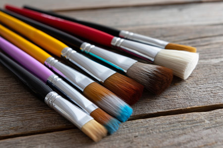 Colorful paintbrushes arranged neatly on a wooden surfaceの素材