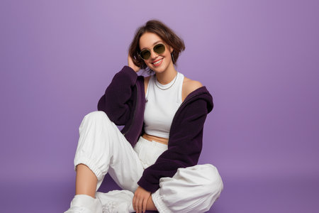 Young woman in stylish outfit posing against a purple backgroundの素材