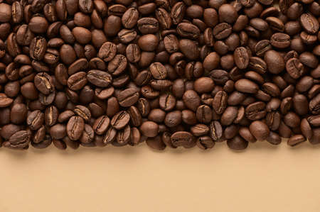 Roasted coffee beans on beige background with copy space. Close up top view. High quality photo