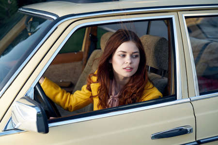 Beautiful young woman in the car, a woman is riding in a retro car.の写真素材
