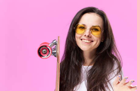 A woman with a skateboard in her hands. Woman in the studio with skateboard.の写真素材