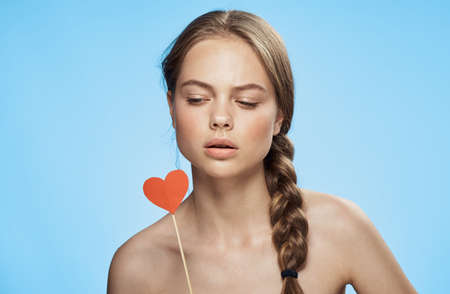 Woman is looking at an accessory heart on a blue background.の写真素材