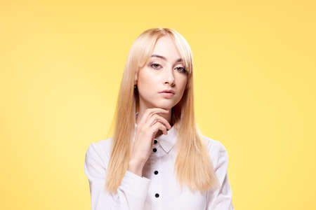 Blonde in a white shirt, woman on a yellow background.の写真素材