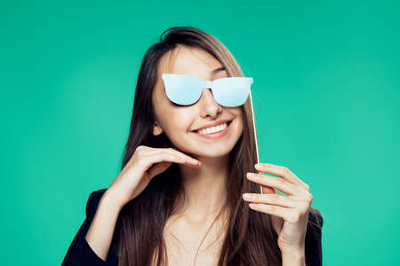 Woman with an accessory glasses on a turquoise background.の写真素材
