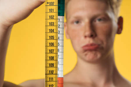 Sports man shows body meter on yellow background.の写真素材