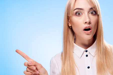 Surprised blonde in a white shirt on a blue background portrait.の写真素材