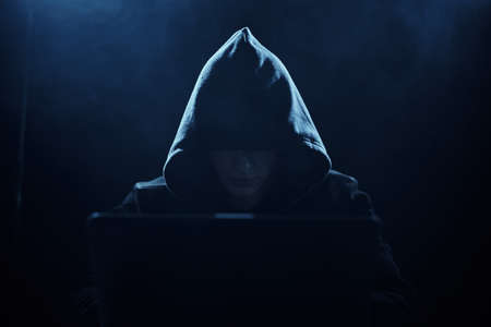 Hacker in a hood on a dark background.の写真素材