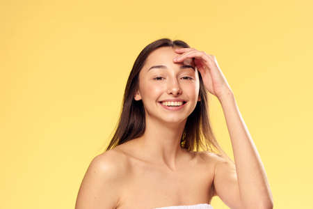 Woman with a smiling hand touched her face on a yellow background.の写真素材
