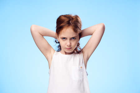 Serious girl holding her hair on a blue background.の写真素材