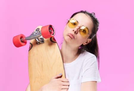 Woman in glasses holds a skate on a blue background.の写真素材