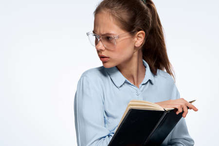 Woman in glasses, a woman is holding a notebook on a light background.の写真素材