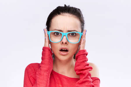 Surprised woman with glasses on a light background.の写真素材