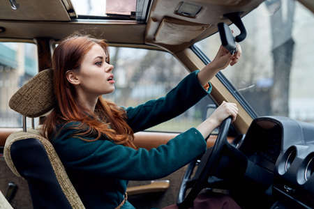 Woman driving a car, a woman fixing a mirror in the car.