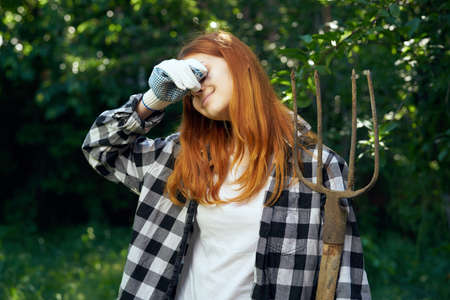 Woman in working gloves, woman holding fork in vegetable garden.の写真素材