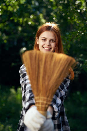 A woman holding a broom at the cottage.の写真素材