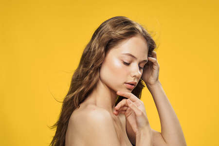 Beautiful woman touches hand to face on yellow background.の写真素材