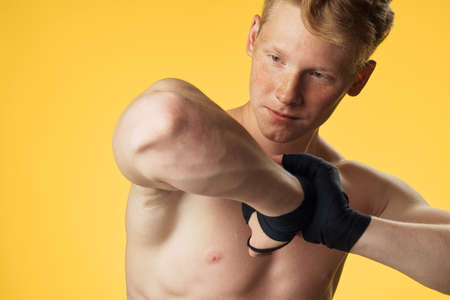Sporty man is engaged in boxing on a yellow background.の写真素材