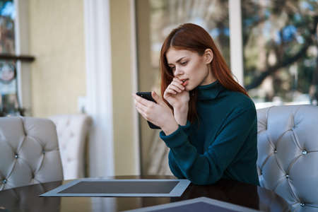 Woman sitting in cafe, woman looking into phone.の写真素材
