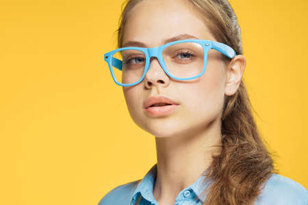 Woman in glasses on a yellow background portrait.