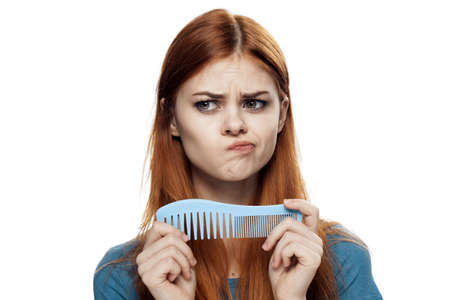 Pensive woman, woman holds a comb on isolated background.