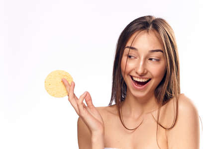 Cheerful woman holds a sponge for the face on an isolated background.の写真素材