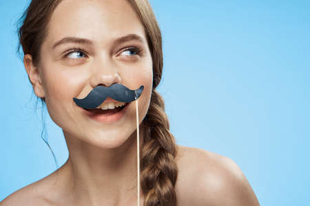Woman smiling, woman with a mustache on a stick on a blue background.
