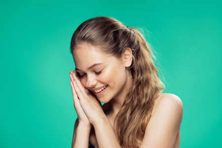 Woman leaning hands to face, woman smiling on green background portrait.の写真素材