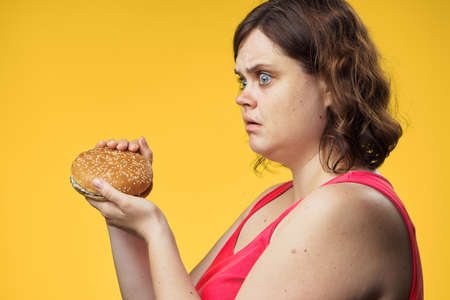 Hungry woman, fat woman eating a hamburger on a white background.の写真素材