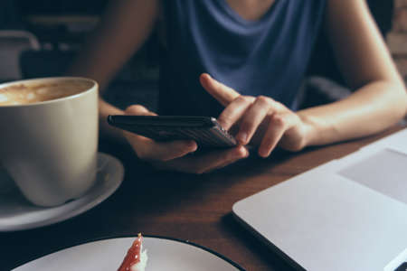 Business woman working at phone, mug with cheesecake.の写真素材