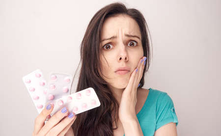 Toothache, a woman has a toothache, a woman with pills, a woman on a light background.の写真素材