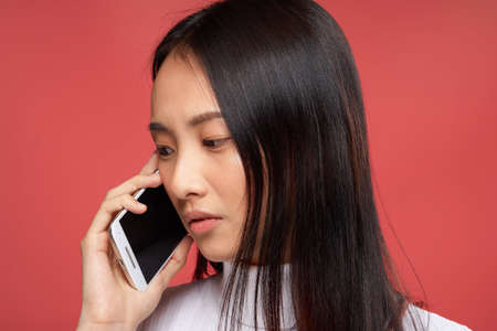 Business woman, Asian woman talking on the phone on a red background portrait.の写真素材
