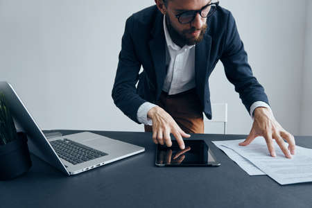 Businessman working in office, businessman looking into documents, businessman with tablet.