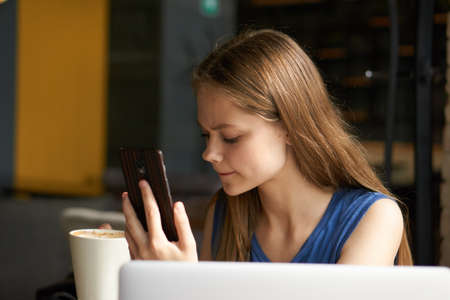 Business woman with phone, woman looking at phone, woman in cafe, coffee.